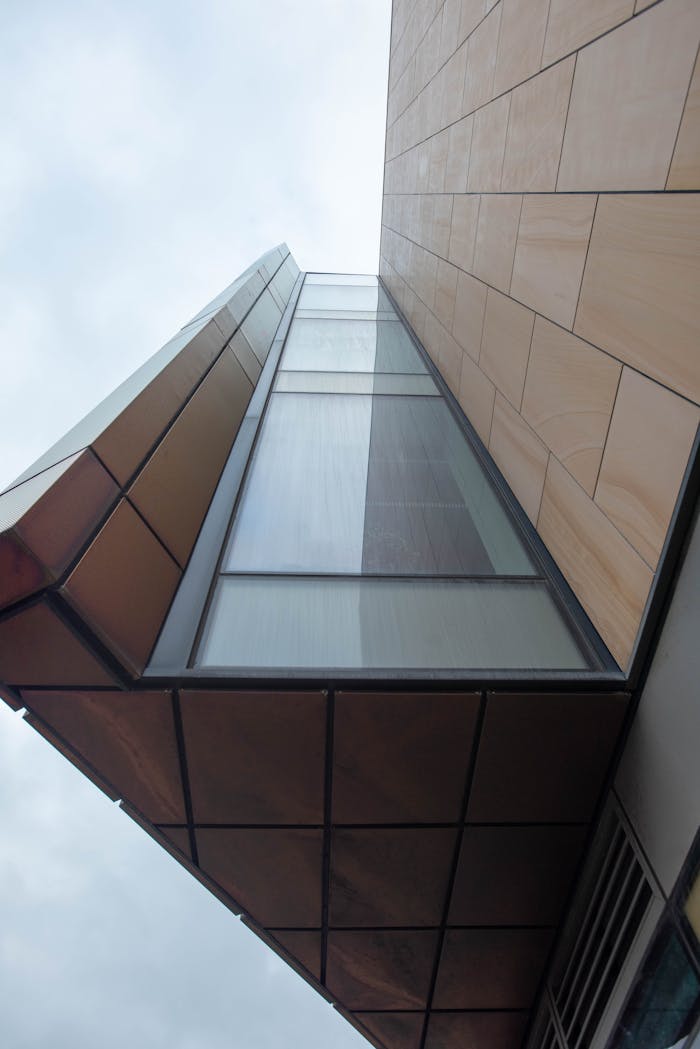 services-01 A striking view of contemporary architecture capturing geometric shapes and glass facade from below.