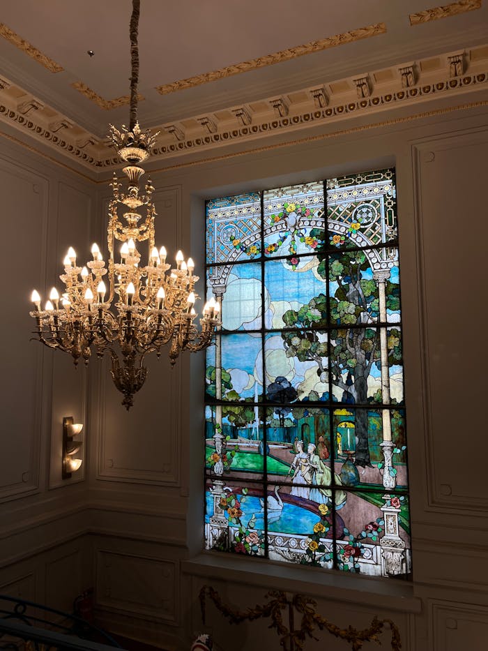 services-04 Elegant interior featuring a golden chandelier and a stunning stained glass window, showcasing artistic heritage.